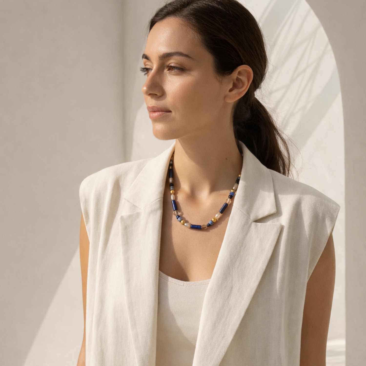 Portrait of model wearing the Athens Necklace, a contemporary blue gemstone beaded necklace with gold-tone details.